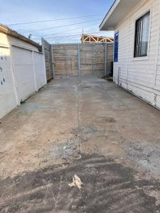 a garage with a fence next to a building at Casa en Pichilemu acogedora y amplia Casa Lile in Pichilemu