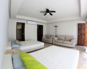 un soggiorno con 2 letti e un ventilatore a soffitto di Villa con Alberca Princess ad Acapulco