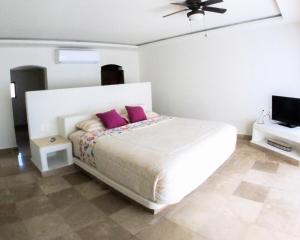 una camera da letto con un letto con cuscini viola e una TV di Villa con Alberca Princess ad Acapulco