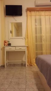 a bedroom with a dresser with a mirror and a television at Studio Mary in Perissa