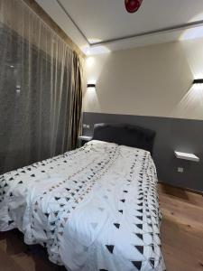 a bedroom with a bed with a white comforter at Studio proche clinique akdital ain sebaa in Casablanca