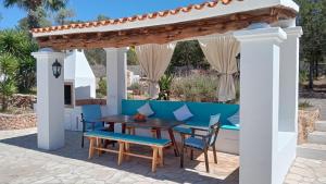 a patio with a wooden table and chairs under a pergola at Casa Puig de Mar, con piscina y jardín' in Sant Josep de Sa Talaia