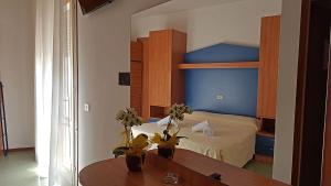 a bedroom with a bed and a table with flowers at Hotel La Fenice in Lido di Jesolo