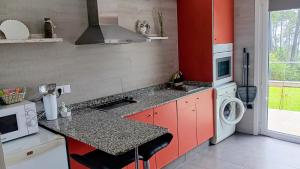 a kitchen with red cabinets and a washing machine at Areos de Cabío in A Pobra do Caramiñal