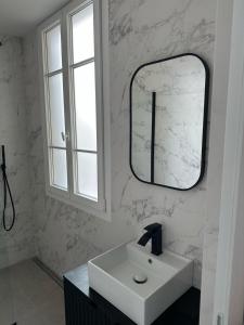 un bagno bianco con lavandino e specchio di Luxury Apartment Champ de Mars Eiffel Tower a La Celle-sous-Gouzon