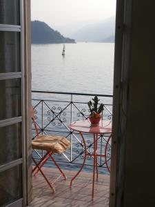 a table and chair on a balcony with a view of the water at Casa sullo Sperone in Varenna