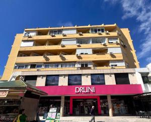 ein hohes Gebäude mit einem Getränkeschild davor in der Unterkunft Apartamento Centro Torremolinos in Torremolinos