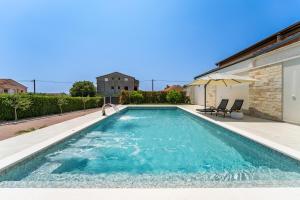 una piscina con sombrilla y 2 sillas en Villa 65 Large 55m2 Private Heated Pool Peaceful Escape, en Škabrnje