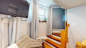 a living room with a television and a stairway at Near Public Transport, Fenway, Bu, Longwood Med in Brookline