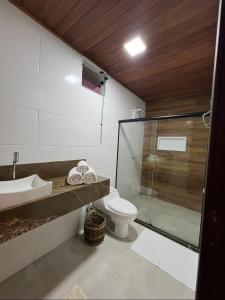 a bathroom with a toilet and a glass shower at Almaré Hospedagem - Boipeba in Cayru