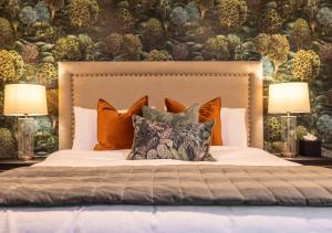 una camera da letto con un letto grande con cuscini di The Glasshouse by MajorDomo - Central Home with Hot Tub & Sauna a Queenstown