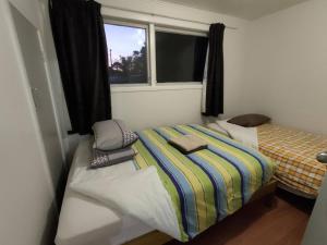 a small bedroom with two beds and a window at 3 Bedroom Serviced House A, 30 Laurel St in Auckland