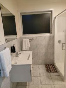 a white bathroom with a sink and a shower at 3 Bedroom Serviced House A, 30 Laurel St in Auckland