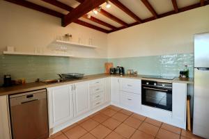 a kitchen with white cabinets and a stove top oven at Maleny-Montville Cottages #1 - 2 bed ocean views in Balmoral Ridge +20 photos