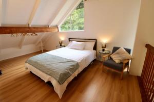 a bedroom with a bed and a window and a chair at Maleny-Montville Cottages #1 - 2 bed ocean views in Balmoral Ridge