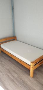 a bed with a wooden frame and white mattress at Studio lit 90 avec balcon in Gradignan