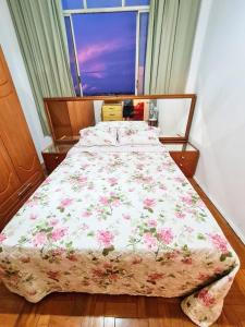 a bedroom with a bed with a floral comforter and a window at Radiante Amanhecer! in Belo Horizonte +26 photos