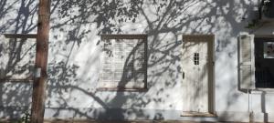 a building with two windows and a shadow of a tree at Alquilo Casa en Barrio Bombal in Barraquero