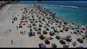 a crowd of people on a beach with umbrellas at ADAapartmenthousesalerno in Salerno