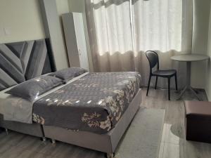 a bedroom with a bed and a chair and a window at Hotel Samana'Inn in Arequipa