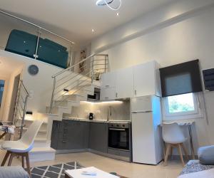 a kitchen with white cabinets and a spiral staircase at Elision in Skala Marion