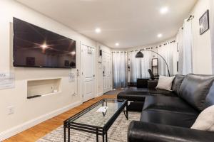 a living room with a black leather couch and a tv at Modern & Stylish 1-BR Condo near Downtown in Boston