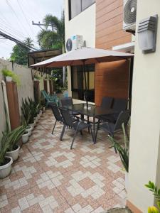 a patio with a table and chairs and an umbrella at Eli's Villa Cebu in Cebu City
