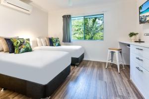 een slaapkamer met 2 bedden en een keuken met een raam bij Sunset Water Premium 2 bedroom in Hamilton Island