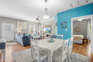 a dining room and living room with a white table and chairs at Paradise Found Gulf Shores Beach Pools Dogs in Gulf Shores