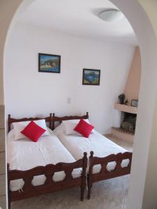 um quarto com 2 camas e almofadas vermelhas em Kalotina's Apartments em Emborios