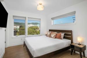 a white bedroom with a bed and two windows at The Sandmark in Rockaway Beach