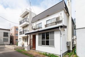 a white building with balconies on a street at J style villa Sapporo フルリフォーム 長期滞在にもオススメ マーケット近く in Sapporo