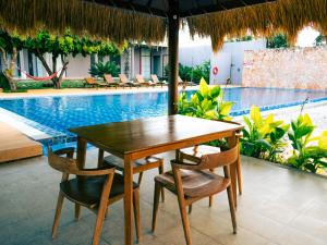 a wooden table and chairs next to a swimming pool at Kambaniru Beach Hotel and Resort in Waingapu