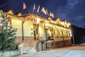 Un edificio con luci e bandiere natalizie sopra. di Hotel Šomka a Drienica