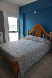 una camera da letto con un letto in legno con una parete blu di Cielo Apart- Departamento Céntrico a San Luis
