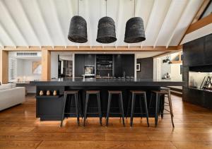 una cocina con una gran isla negra con taburetes de bar en Aroha Homestead Luxury Holiday Home by MajorDomo, en Arrowtown