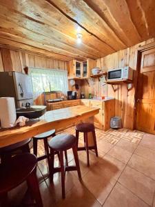 a kitchen with a wooden table and some stools at Casa de campo Ecos del Poás in Dulce Nombre