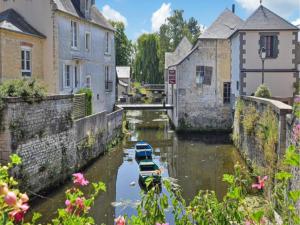 two boats are docked in a canal between buildings at Golden Light Cottage Escape in Sainte-Marguerite-dʼElle