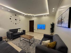 a living room with two couches and a clock on the wall at Al Diyafah Apt in Medina