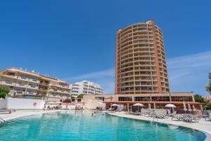 een hotelzwembad met een hoog gebouw op de achtergrond bij Sea Top Flat II in Portimão