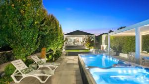 un patio trasero con bañera de hidromasaje, sillas y una casa en Amore Bowral, en Bowral