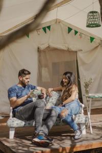 a man and a woman sitting in front of a tent at Glamping Traslasierra Carpa Norte in San Javier +20 photos