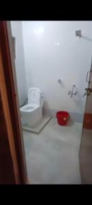 La salle de bains est pourvue de toilettes et d'un seau rouge. dans l'établissement Manan Guest House, à Malpe