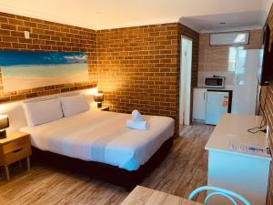 a bedroom with a bed and a brick wall at Buccaneer Motel in The Entrance