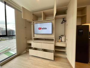 un salon avec une télévision dans une pièce avec une fenêtre dans l'établissement Cozy New Loft Coworking Gym Terrace Play Z, à Bogotá