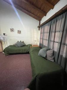 two green beds in a room with a window at Cabañas Nono Mario in San Rafael