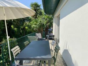 ein blauer Tisch und Stühle auf einem Balkon mit einem Sonnenschirm in der Unterkunft Maison rénovée à Cambo, 2 ch, jardin, parking, WiFi - FR-1-495-154 in Cambo-les-Bains