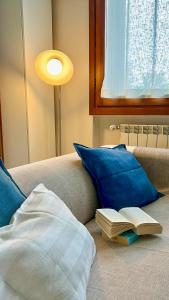 - un livre sur un canapé avec une lampe et un oreiller dans l'établissement Domus Felix Ferienhaus, à San Felice del Benaco