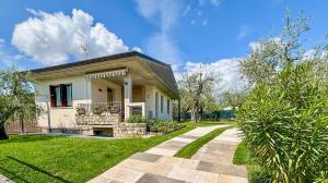 une petite maison blanche avec une cour gazonnée dans l'établissement Domus Felix Ferienhaus, à San Felice del Benaco