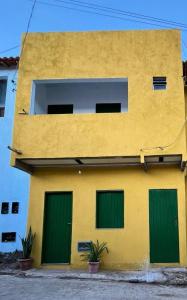 a yellow and green building with green doors at hospedagem dos viajantes in Lençóis